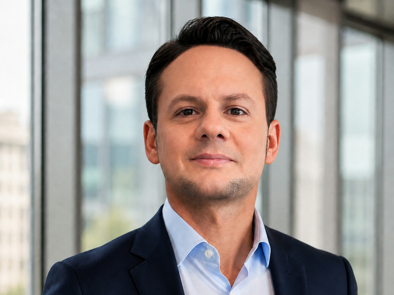 Jared Mastroianni wearing a navy blazer and light blue shirt in a contemporary office setting.